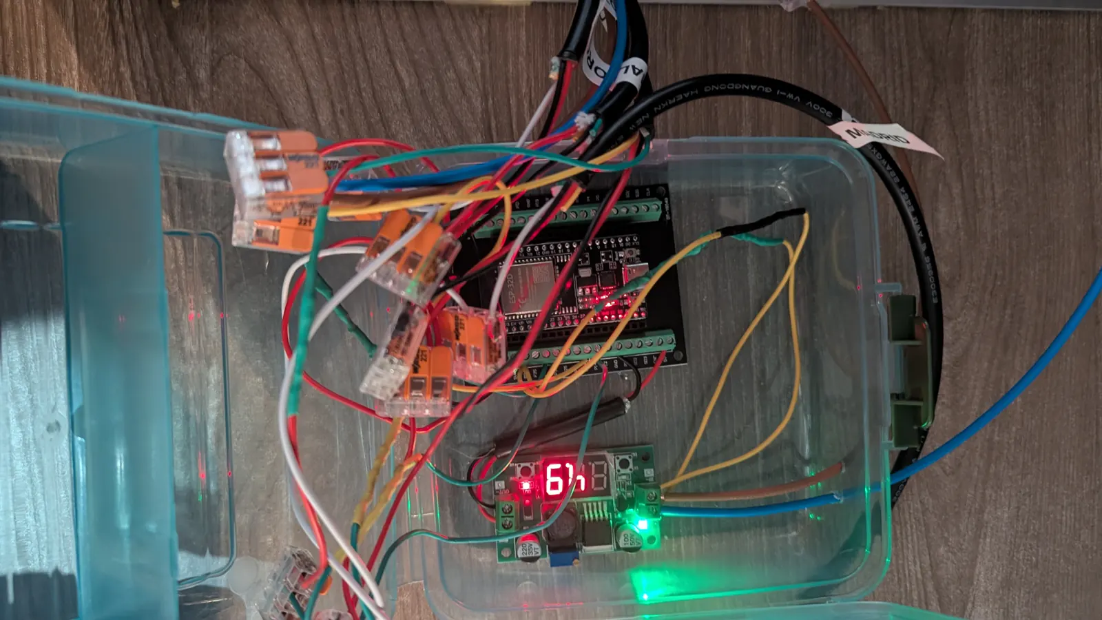 La caja de la electrónica, con el ESP32 en su placa de bornas, el buck y las conexiones